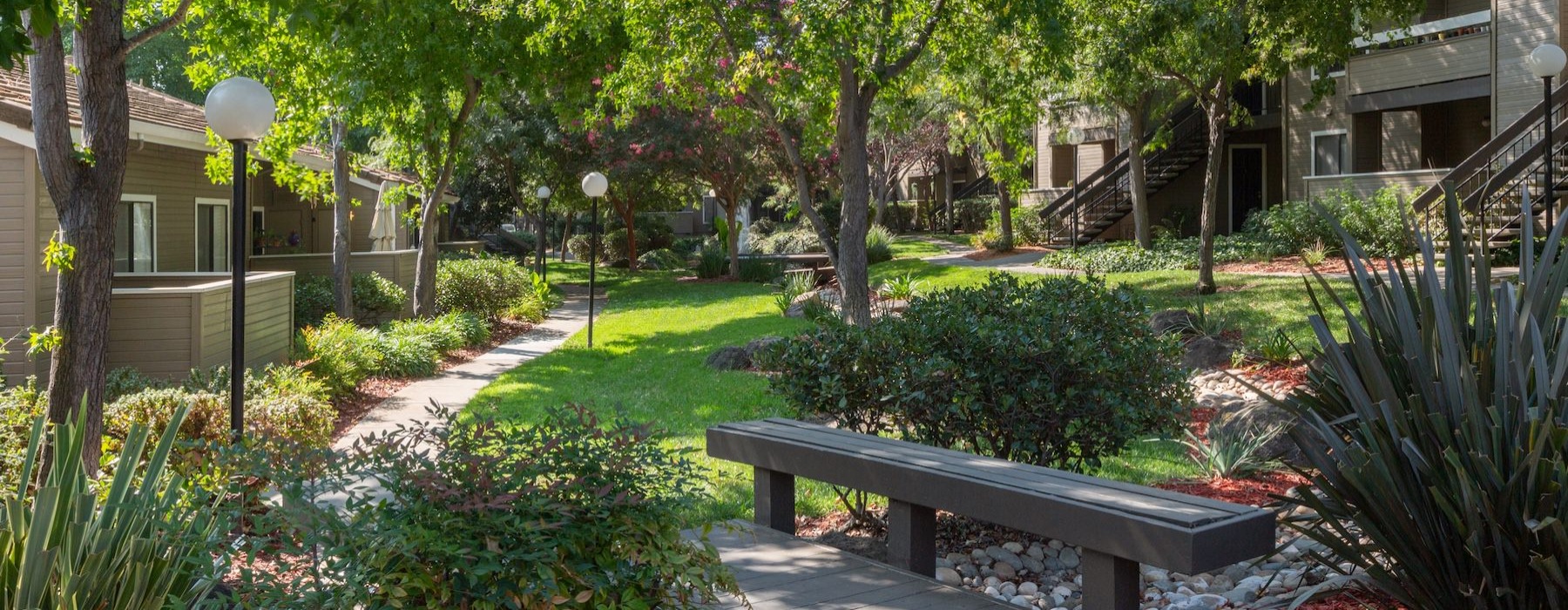 a walking trail with a bench in a neighborhood