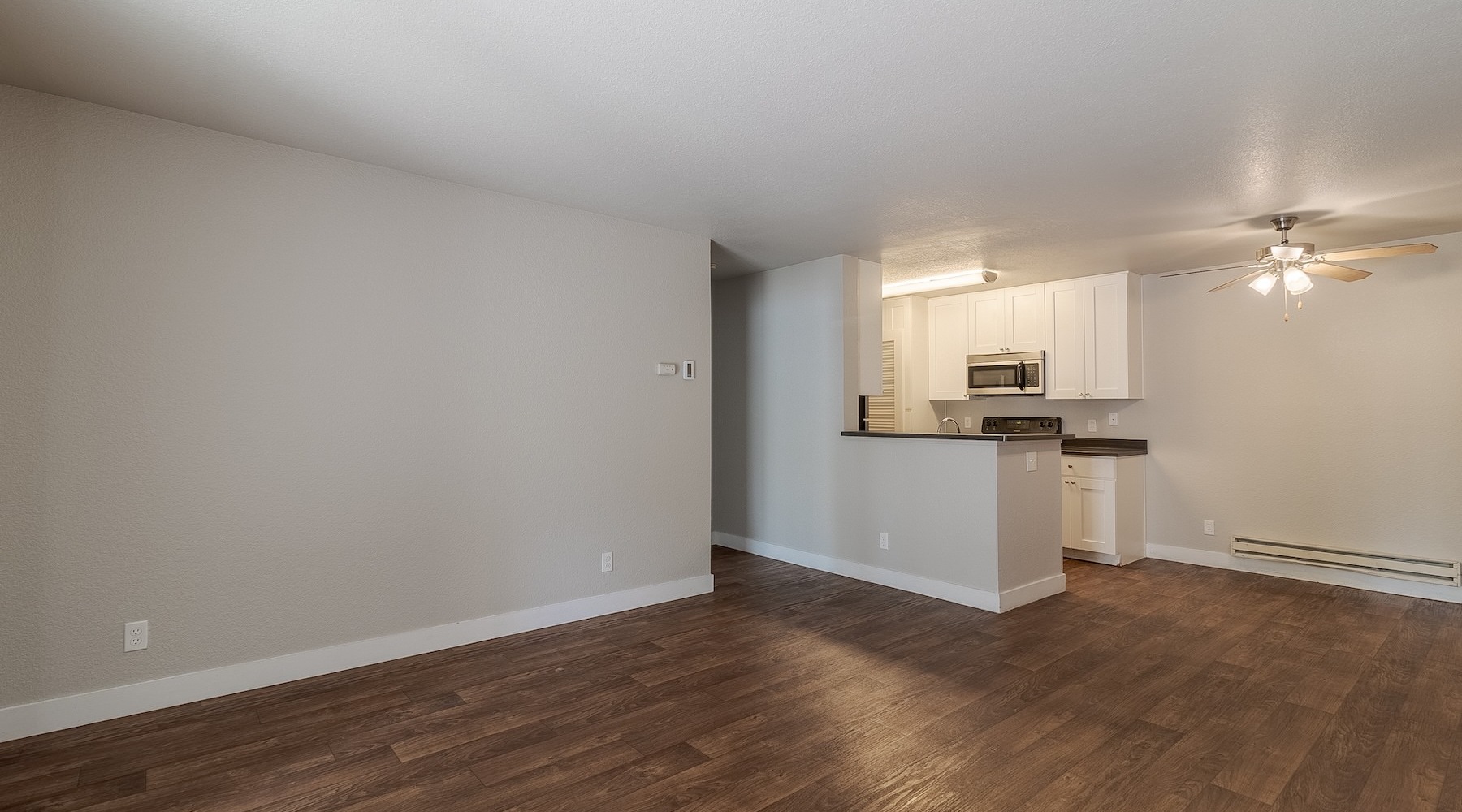 an empty living room and kitchen with wood floors